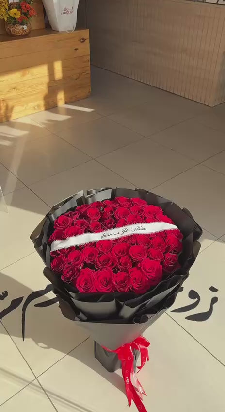 باقة الورد الاحمر مع شريطة طالبين القرب منكم